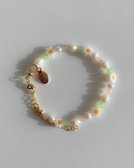 A studio shot of Buttercup Studio's Daisy For You Freshwater Pearls Bracelet. Features freshwater pearls in assorted colours and sizes, green beads and daisy charms.