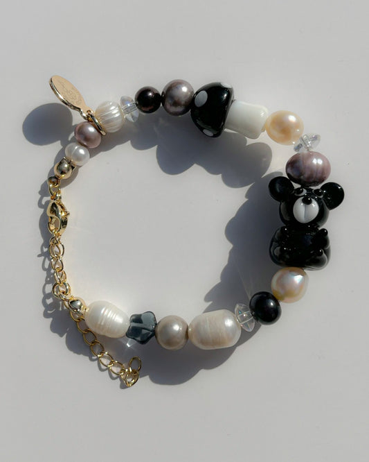 A studio shot of Buttercup Studio's Onyx Teddy Freshwater Pearls Bracelet. Made with assorted freshwater pearls, clear beads, a special black mushroom lampwork glass bead and a special black teddy lampwork glass bead.