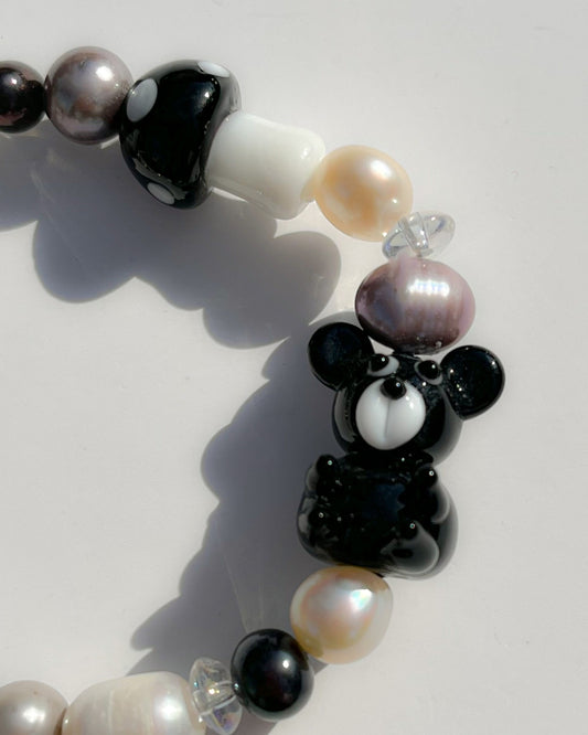 A close up studio shot of Buttercup Studio's Onyx Teddy Freshwater Pearls Bracelet. Made with assorted freshwater pearls, clear beads, a special black mushroom lampwork glass bead and a special black teddy lampwork glass bead.