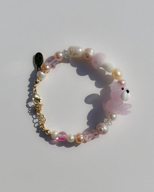 A studio shot of Buttercup Studio's Strawberry Beary Freshwater Pearls Bracelet. Made with assorted freshwater pearls, clear pink beads, a lampwork glass pink mushroom bead and a lampwork glass pink teddy bead.