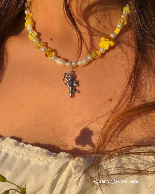 A close up of @trendy_fashioninspo on Instagram wearing a Custom Fairy Cherub Pendant Necklace by Buttercup Studio. Handmade with freshwater pearls, yellow charms and a silver cherub in the center.