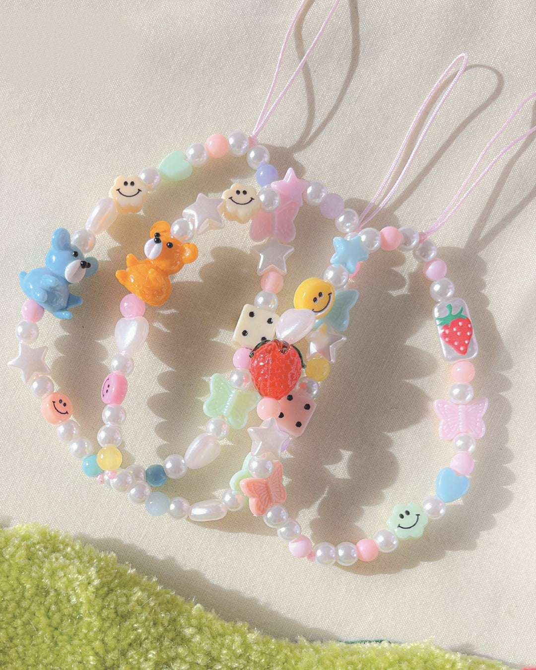 A studio shot of three Buttercup Studio Dream Custom Phone Straps, made with a variety of unique pearls, charms and glass beads.