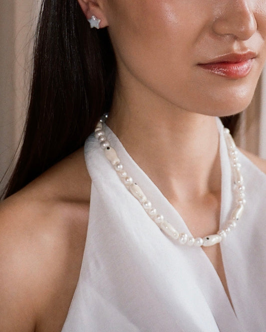 A close-up model shot of The Lucky Fish Freshwater Pearl Necklace is made using high quality AA+ freshwater pearls and glazed Milky fish ceramic fish beads. Finished with 14k gold clasps and adjustable chain. This exclusive Buttercup Studio item is a limited edition and unisex. 