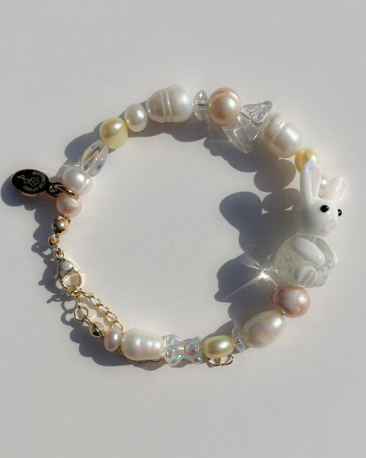 A studio shot of Buttercup Studio's Honey Bunny Freshwater Pearls Bracelet. Made with assorted freshwater pearls, clear beads and a special white bunny lampwork glass bead.