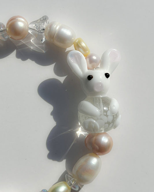 A close up studio shot of Buttercup Studio's Honey Bunny Freshwater Pearls Bracelet. Made with assorted freshwater pearls, clear beads and a special white bunny lampwork glass bead.