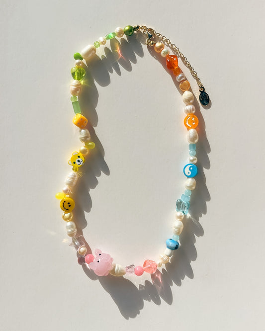 Studio shot of a sample Buttercup Studio Custom Freshwater Pearls Necklace. Colourblocked with freshwater pearls and orange, blue, pink, yellow and green beads and charms.