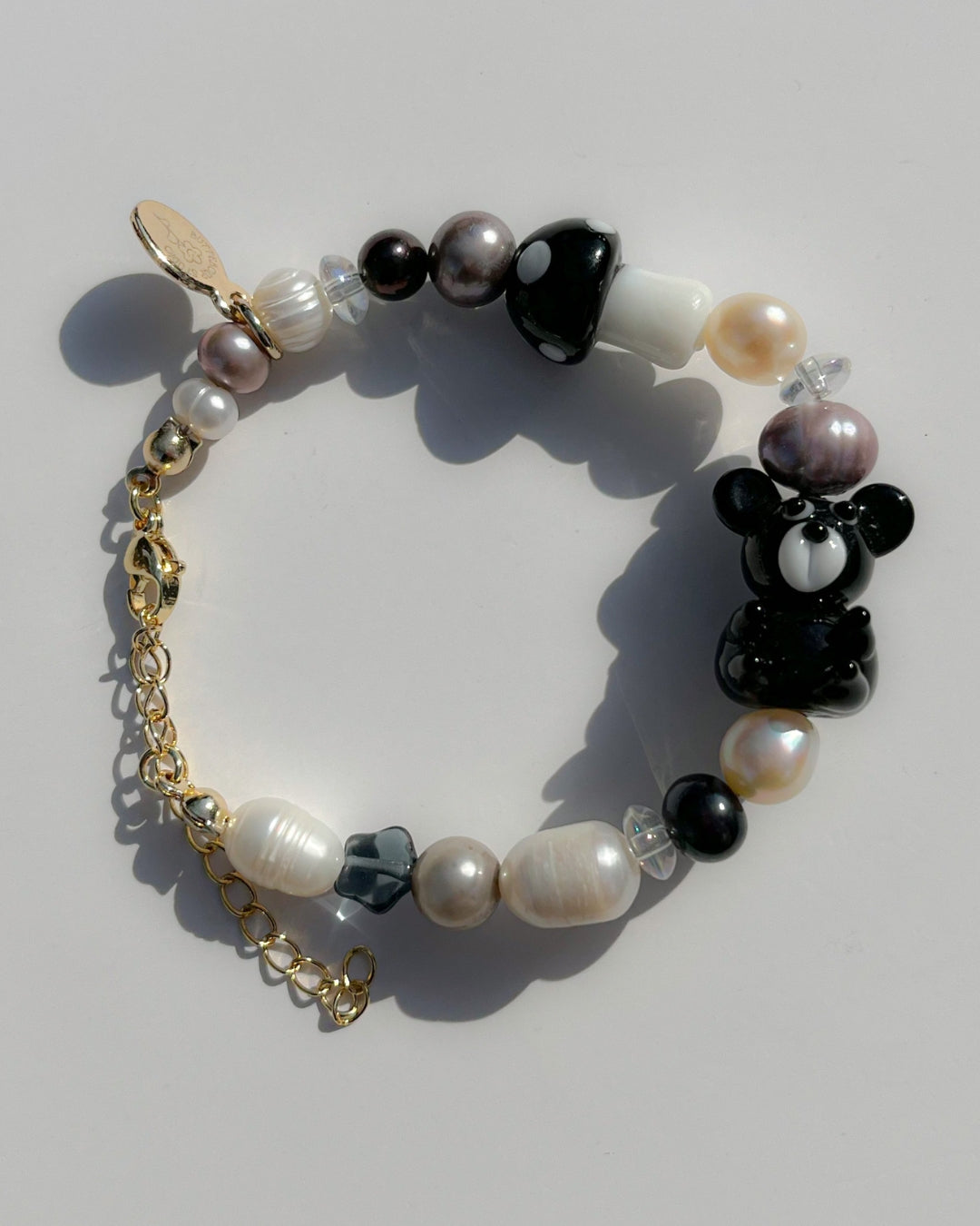 A close up studio shot of Buttercup Studio's Onyx Teddy Freshwater Pearls Bracelet. Made with assorted freshwater pearls, clear beads, a special black mushroom lampwork glass bead and a special black teddy lampwork glass bead.