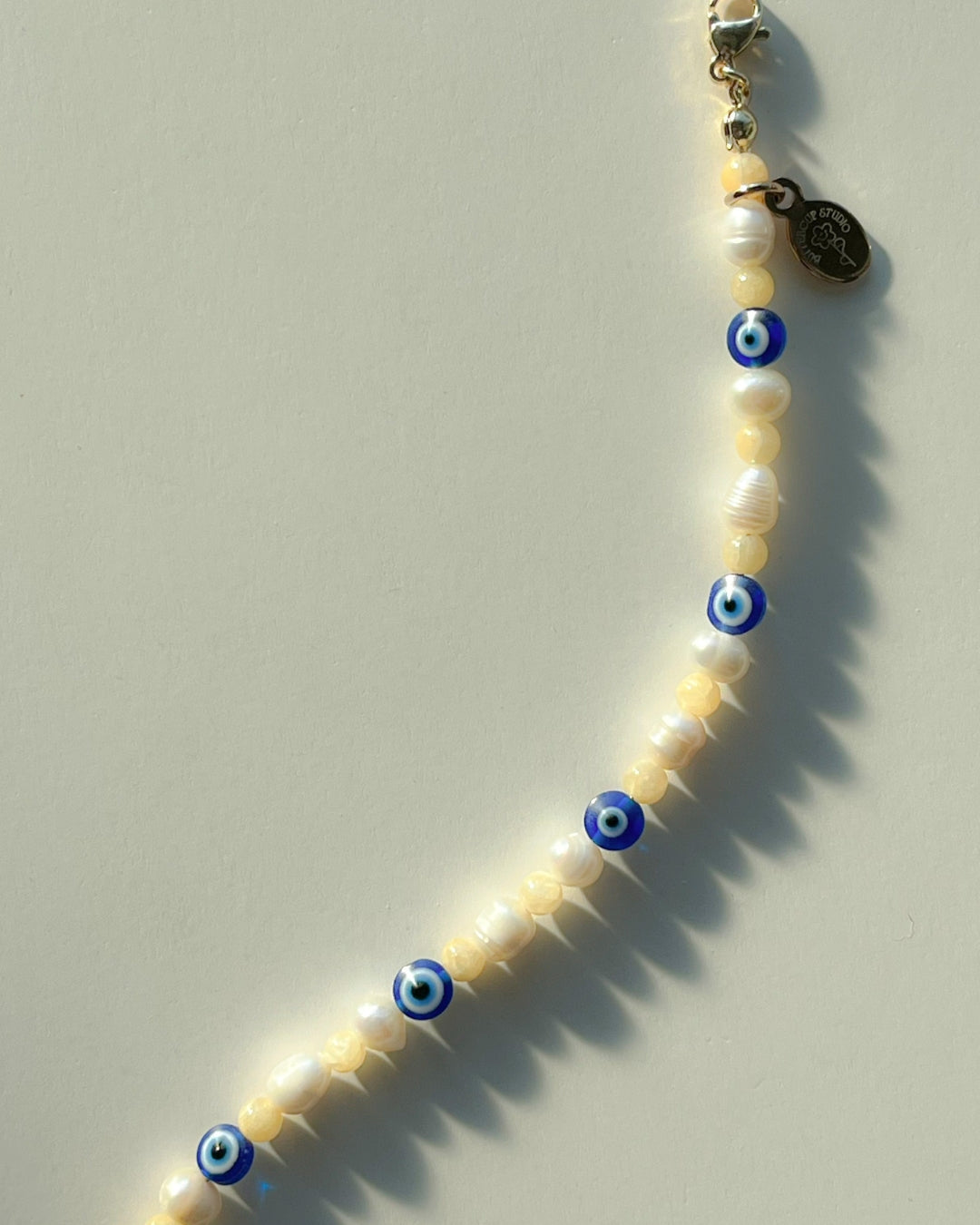 Studio shot of Buttercup Studio's Evil Eye Freshwater Pearls Bracelet. Made with special lampwork glass evil eye beads and assorted freshwater pearls.