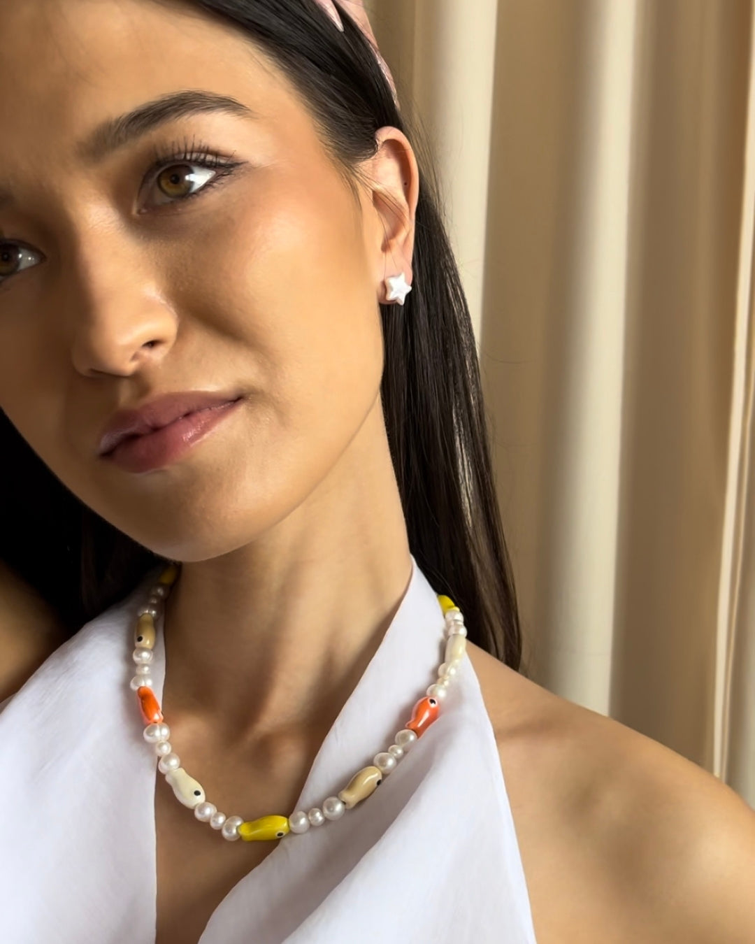 A close-up model shot of The Lucky Fish Freshwater Pearl Necklace is made using high quality rare AA+ freshwater pearls and glazed multi fish ceramic fish beads. Finished with 14k gold clasps and adjustable chain. This exclusive Buttercup Studio item is a limited edition and unisex. 