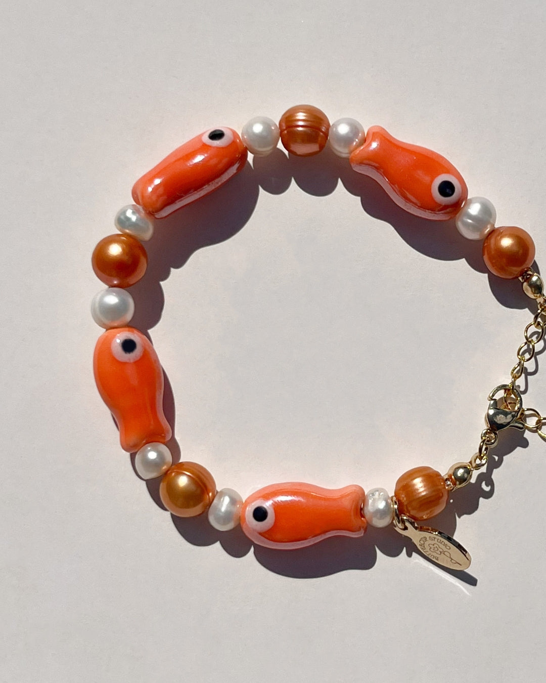 The Lucky Fish Freshwater Pearl bracelet in Creamsicle is made using high-quality AA+ rare copper hue freshwater pearls and glazed orange fish ceramic fish beads. 