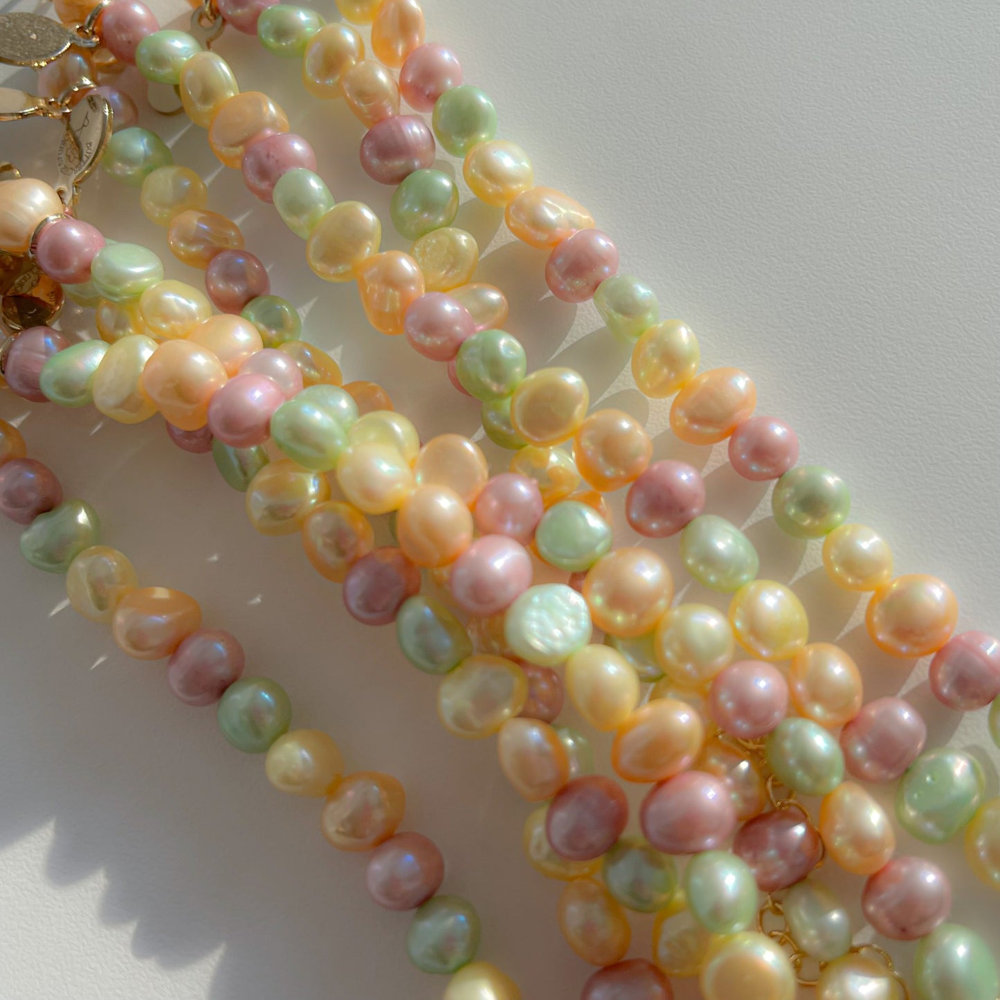 A close up studio shot of multiple Buttercup Studio Timeless Pastel Freshwater Pearls Bracelets. Made with assorted colourful hand selected rare freshwater pearls.