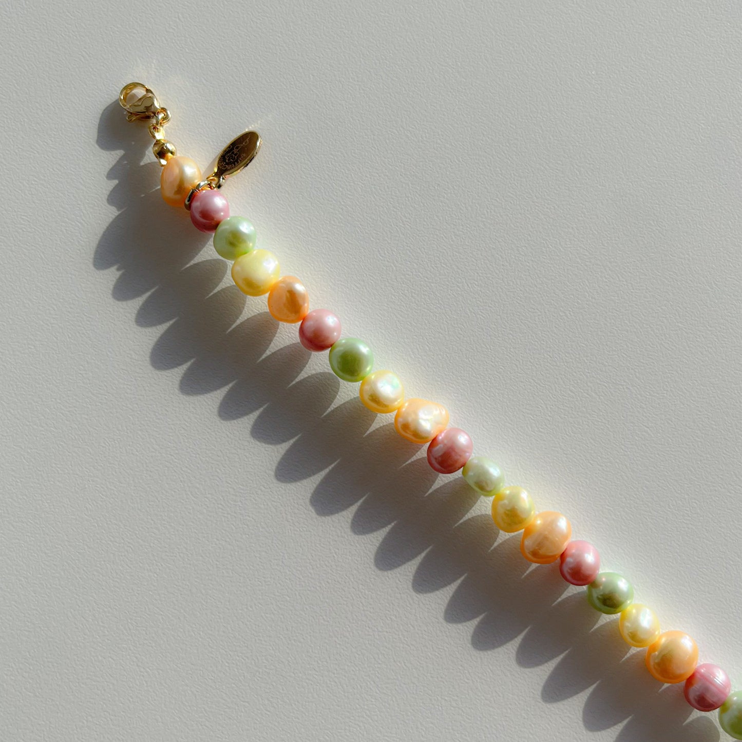 A close up studio shot of Buttercup Studio's Timeless Pastel Freshwater Pearls Bracelet. Made with assorted colourful hand selected rare freshwater pearls.